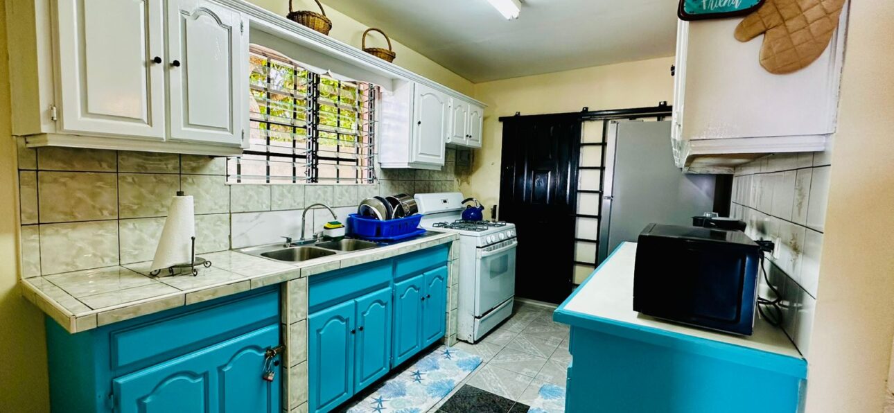 Bright Tobago kitchen with white and blue cabinets, tile flooring, and cozy island decor.