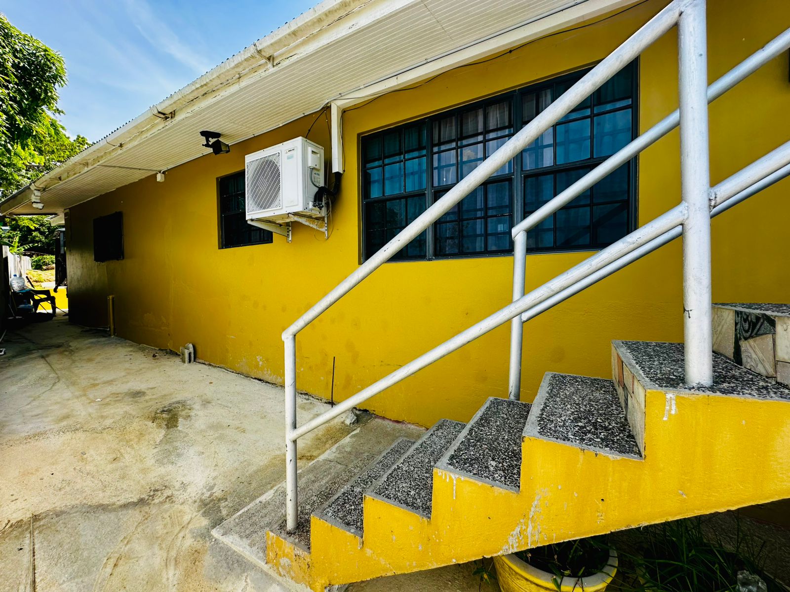 Bright yellow Tobago vacation rental with stairs, air conditioning, and large windows at Seaview Escape Tobago.